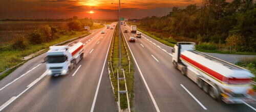 Autobahn bei Sonnenuntergang mit Lastwagen und anderen Fahrzeugen