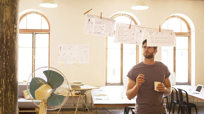 Pensive causal businessman reviewing hanging diagrams in open office