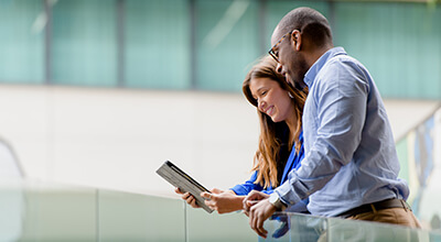 Man and woman on balcony, looking at tablet