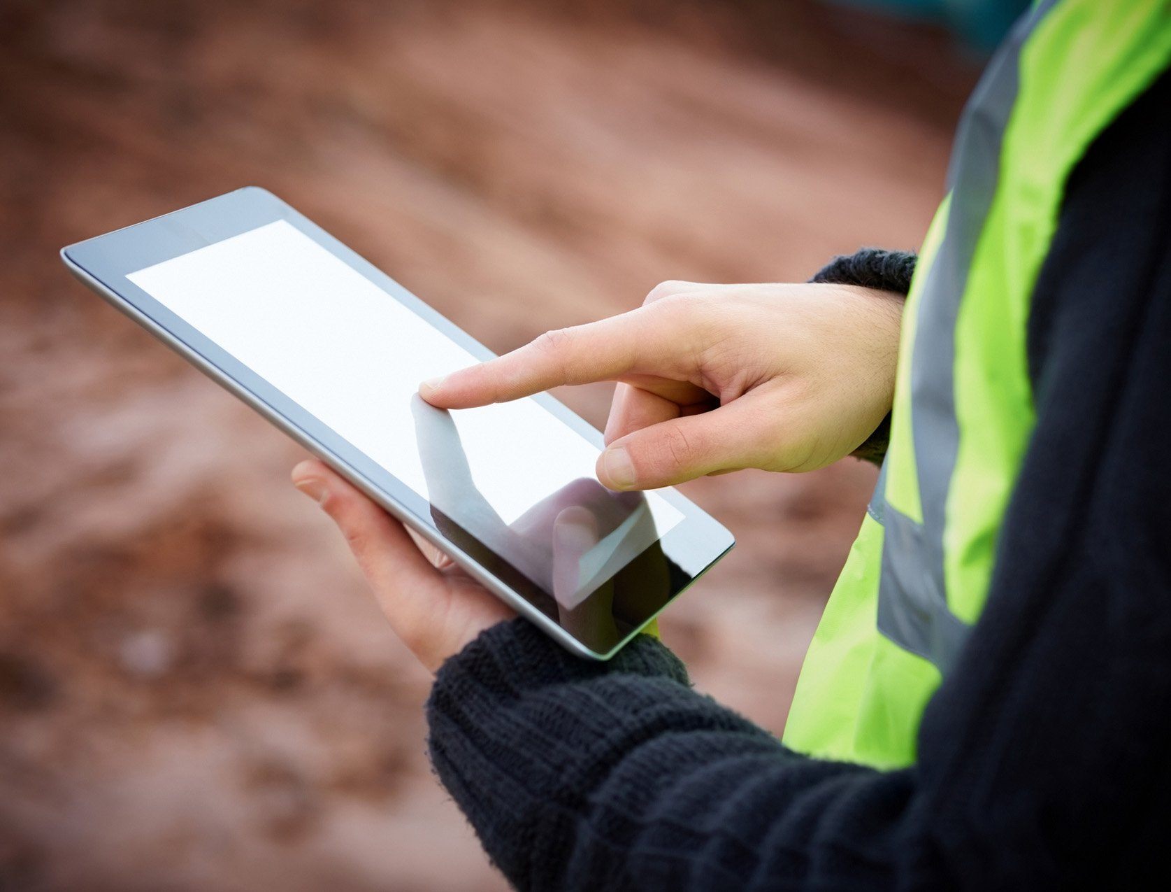 man in high vis vest holds an ipad