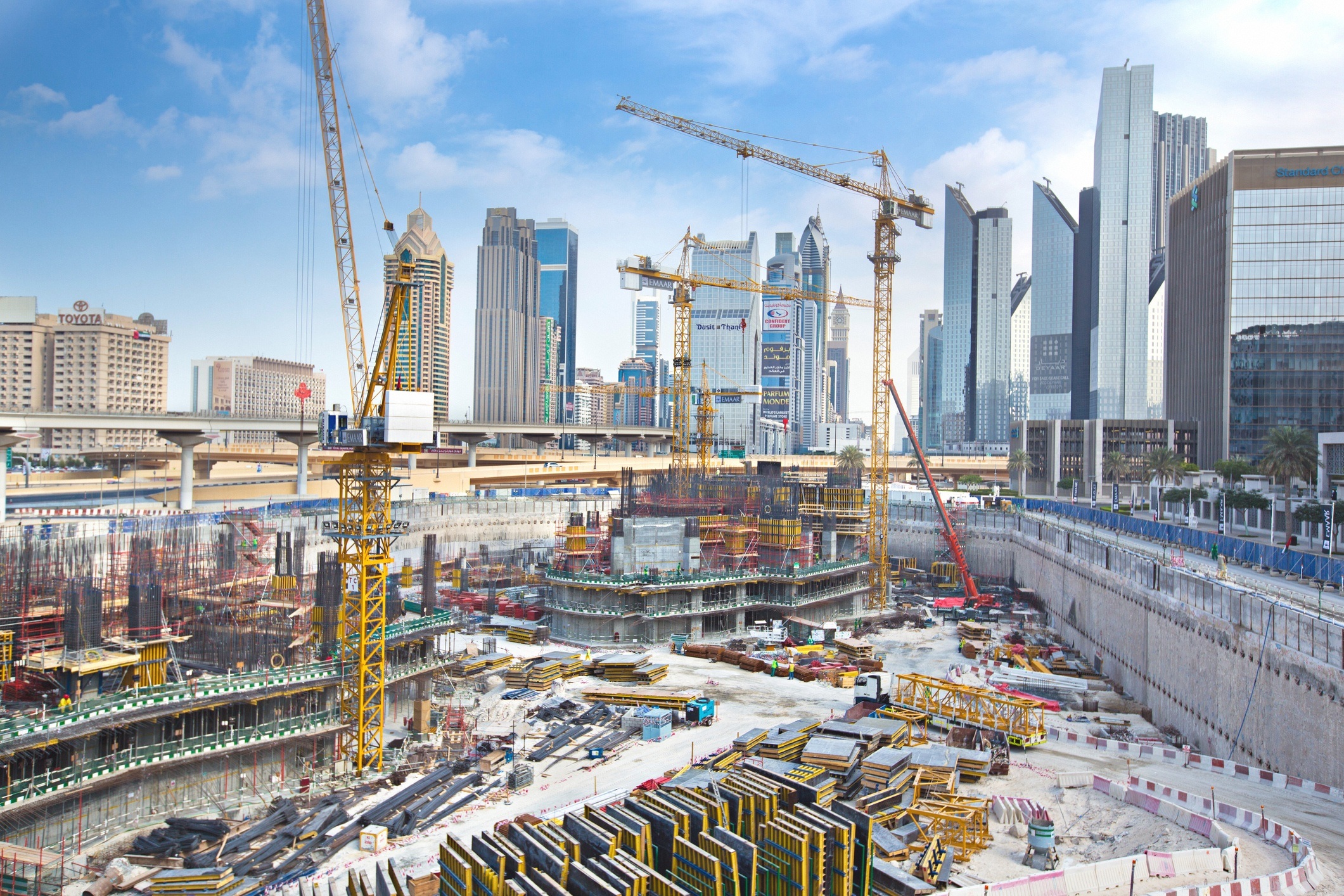 building site pit with yellow cranes in the backdrop of a skyscraper skyline