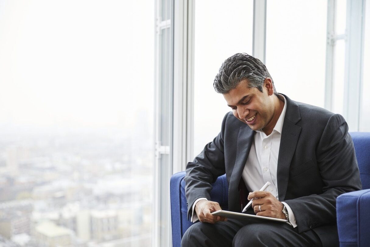 financial futurist CFO looks out at the city while working on his tablet