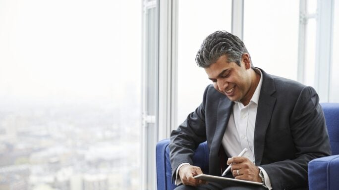 financial futurist CFO looks out at the city while working on his tablet