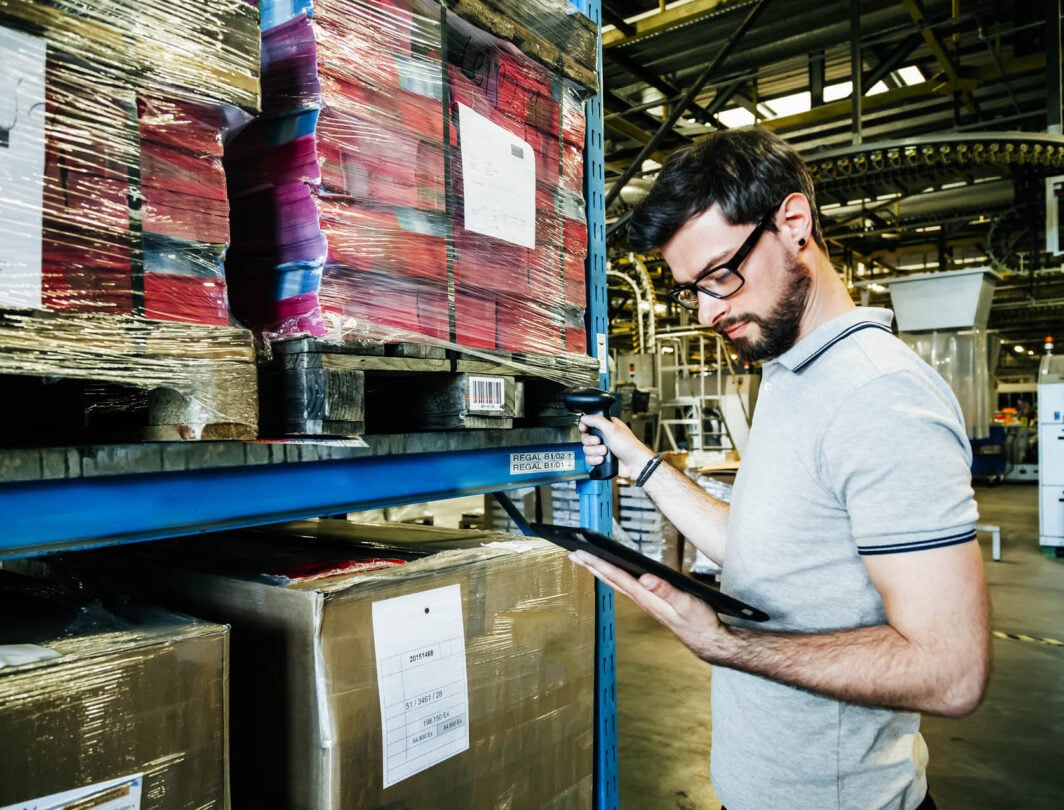 man tracks barcodes and logistics in an erp software warehouse with coloured packages