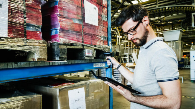 man tracks barcodes and logistics in an erp software warehouse with coloured packages