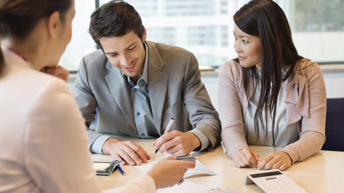 Couple signing documents with business executive