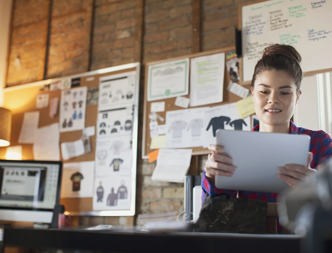 woman holding an ipad in a fashion design studio