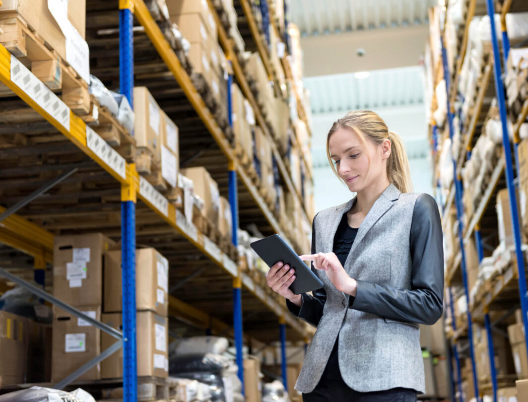 woman examines data on an ipad in a warehouse