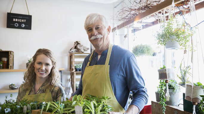Portrait of confident terrarium shop owners holding plants