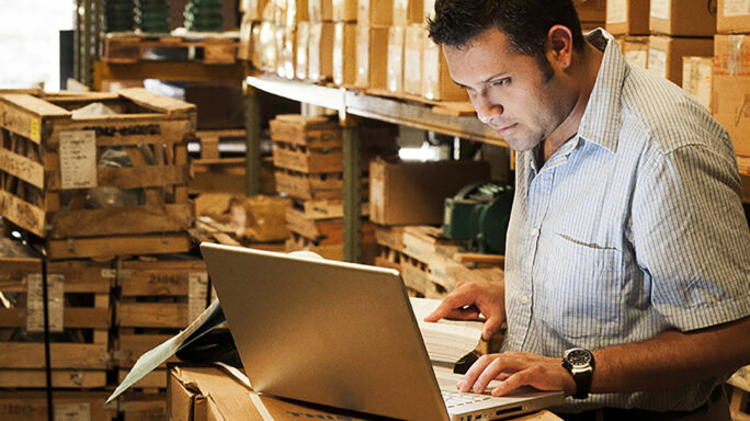 Warehouse manager using a laptop in a warehouse