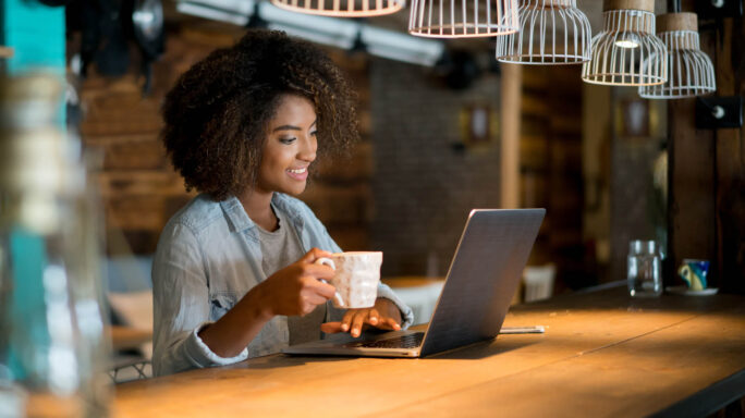 woman works in a cafe with a laptop and a coffee