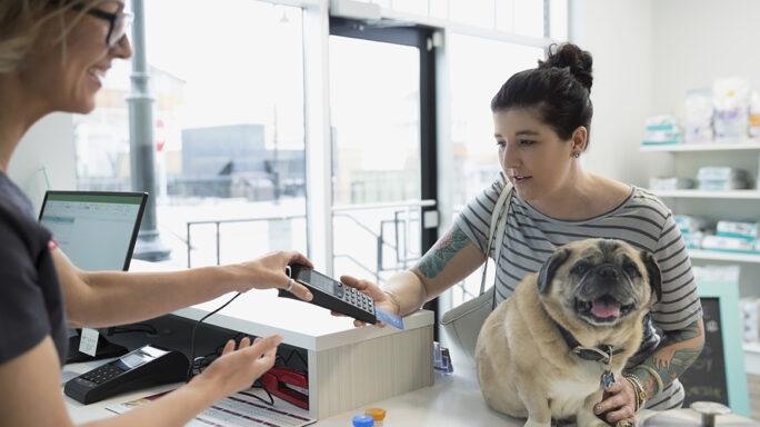 Woman with a dog using the credit card machine in a store