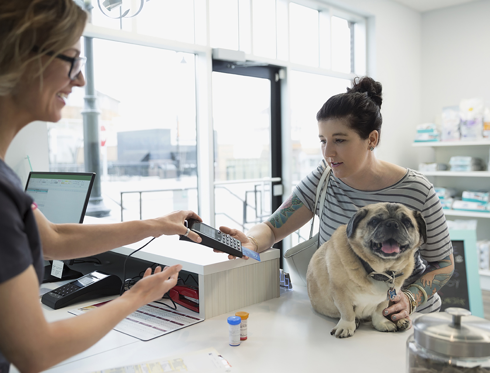 Woman with a dog using the credit card machine in a store