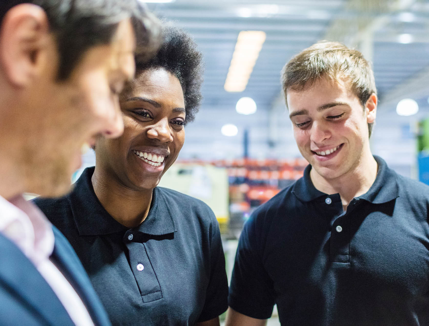 three team members smile with each other in the middle of a warehouse foor