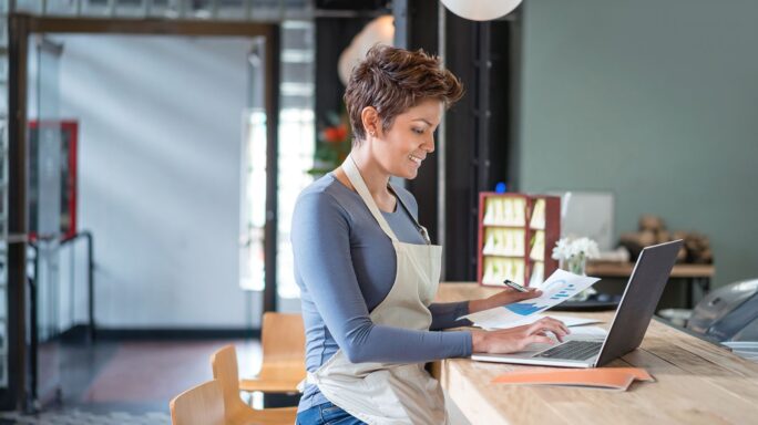 small business owner sits at a cafe and does her finances