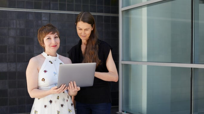 Two women holding an ipad looking at accounting data