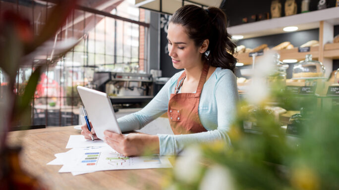 Woman at table reading from tablet and smiling