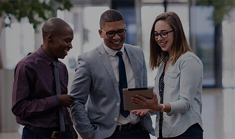 Three ambitious looking young people  look at a tablet device together.