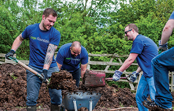 Group of men in Sage foundation t-shirts digging flowerbeds