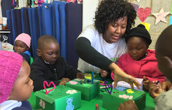 A woman teaching a group of children in a nursery