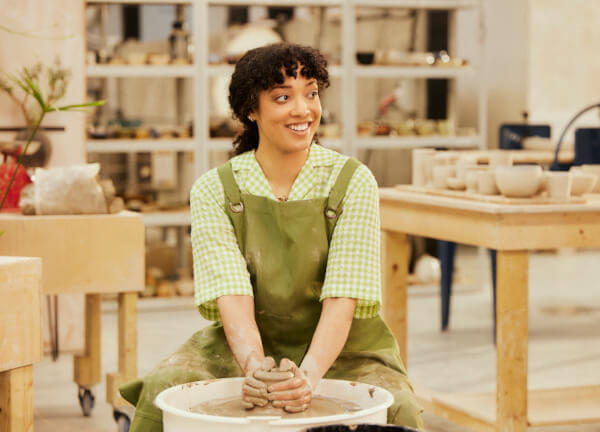  small buiness owner sitting in a studio in front of a pottery wheel