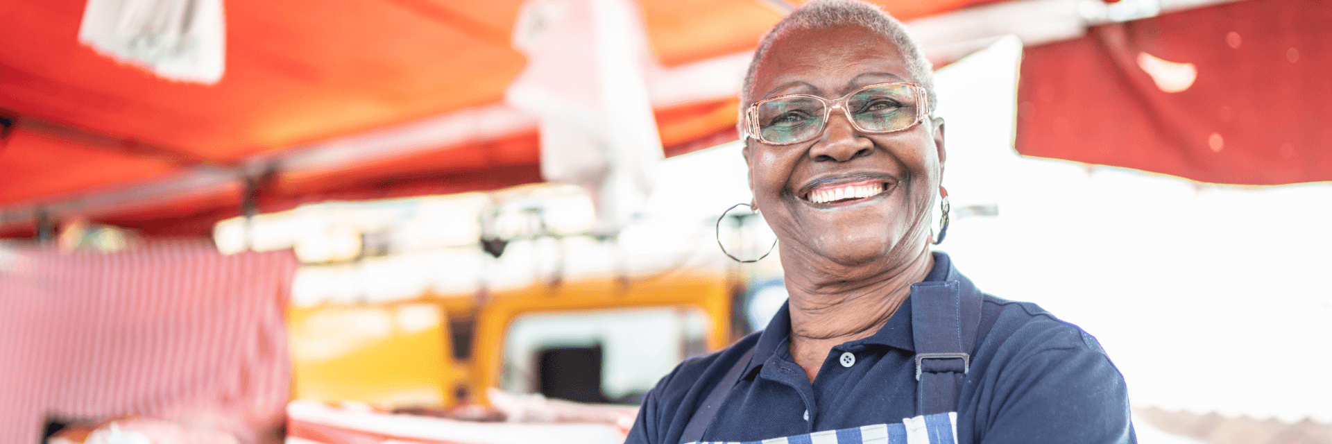 Smiling woman small business owner standing in front of market stall