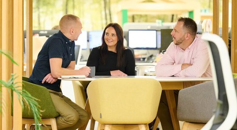  Three colleagues seated around a table having a discussion