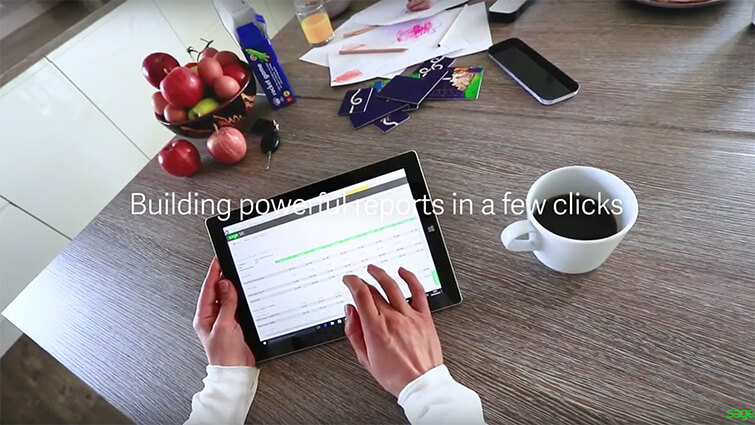 hands holding a tablet with Sage on the screen at a busy breakfast table