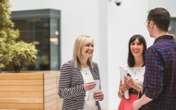 Delivering engagement through experiences ebook cover photo of 3 colleagues chatting in office atrium
