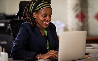 The People team of tomorrow ebook cover photo of woman smiling working on laptop in an open office