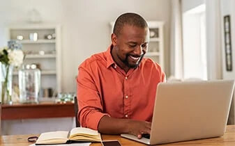 Leading HR into the future report cover photo of man smiling working on a laptop