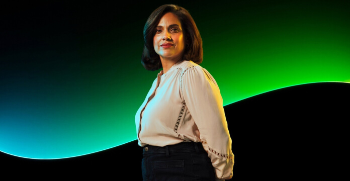  Person standing and looking toward the camera against a green and blue abstract background