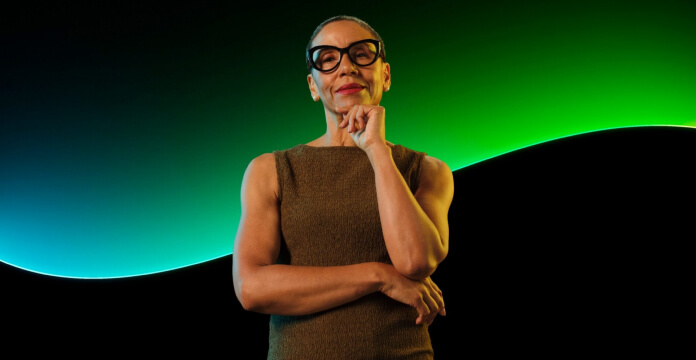  Person posing with folded arms against a green and blue graphic backdrop