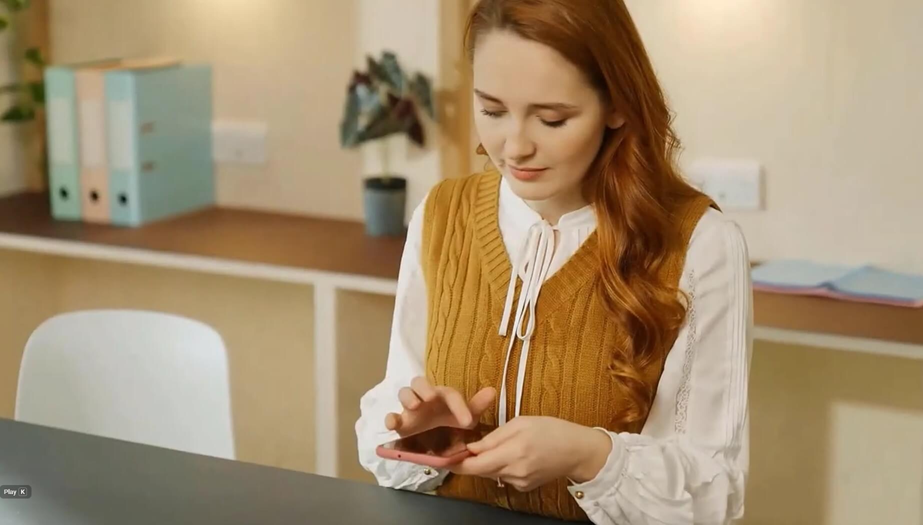  Person using a smartphone while seated at a desk in an office