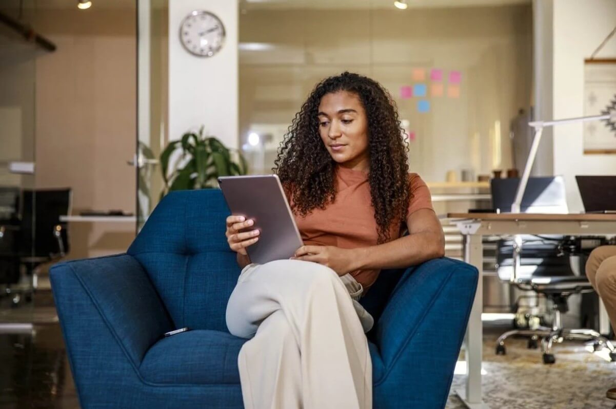  Person seated in an armchair using a tablet in a modern office