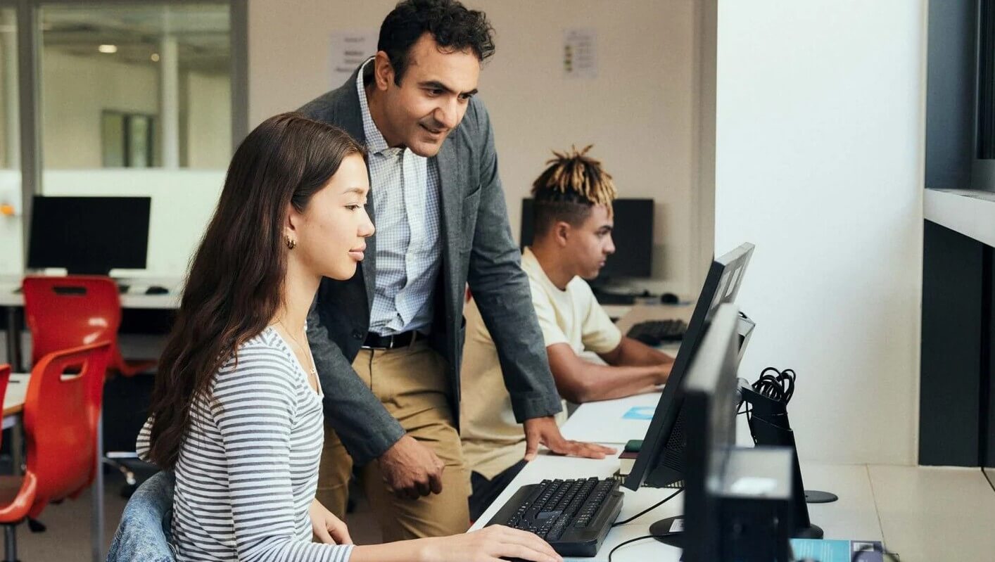  Three people working together at desktop computers in an office