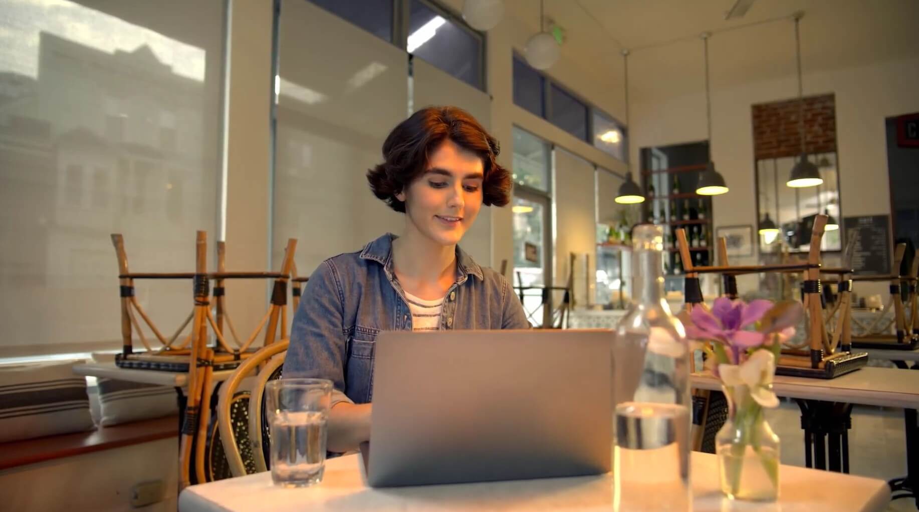  Person working on a laptop at a table in a café or shared workspace