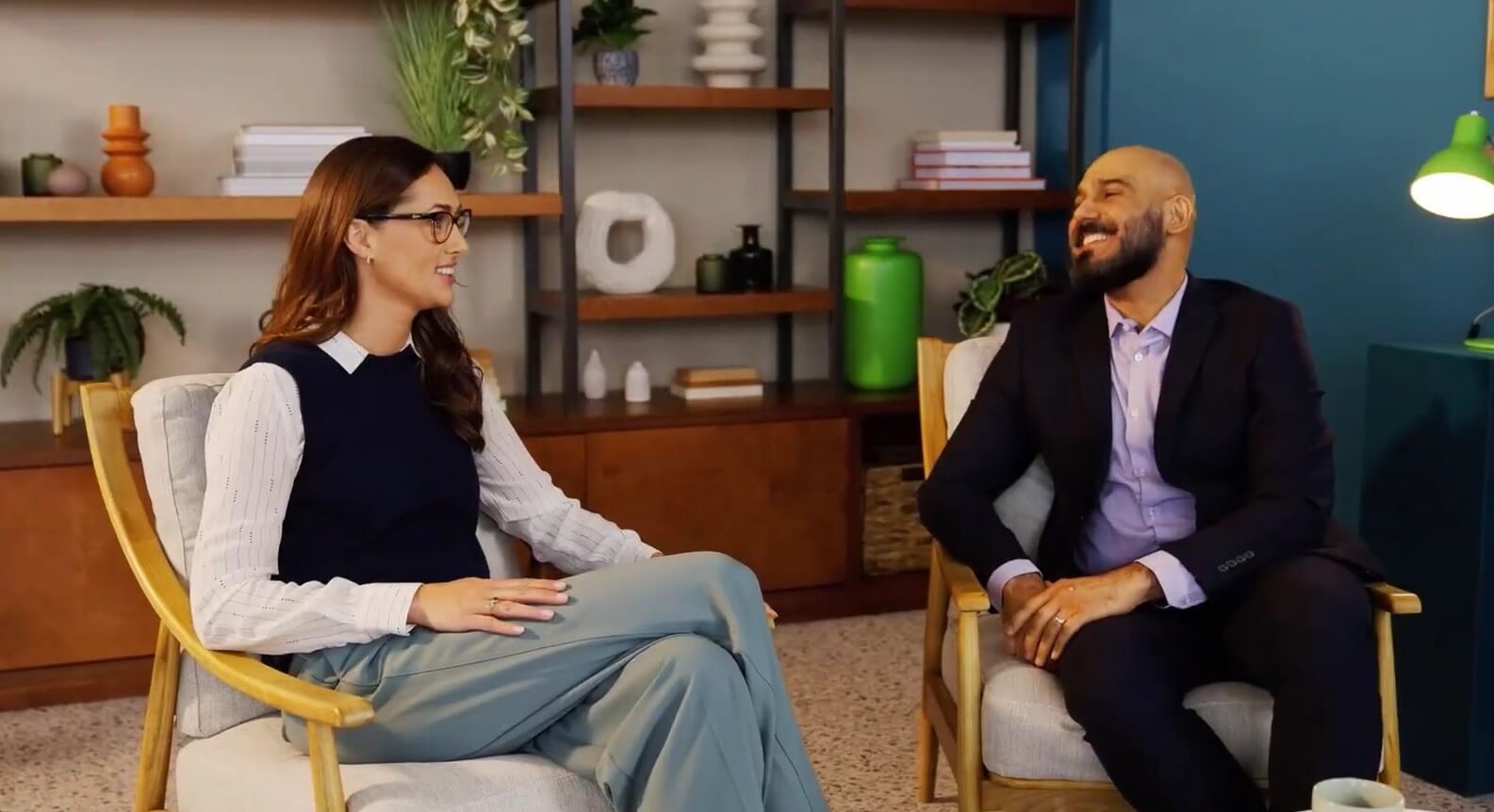  Two people seated in armchairs having a conversation in an office lounge area