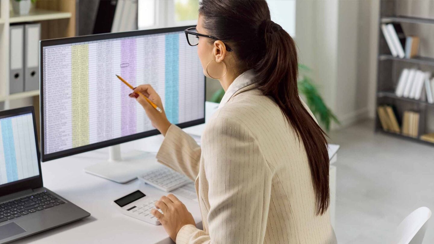 A woman at a desk calculating payroll on a screen using AI