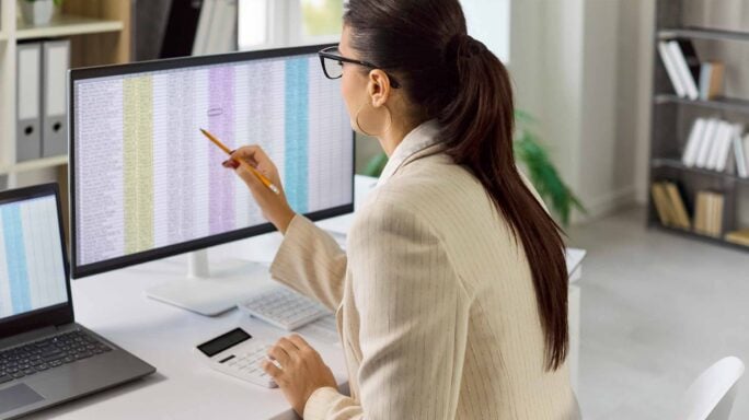 A woman at a desk calculating payroll on a screen using AI