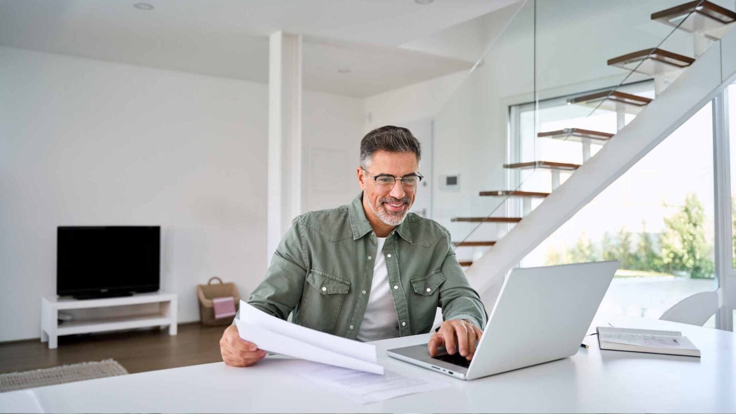 Man at a desk working through papers on a computer