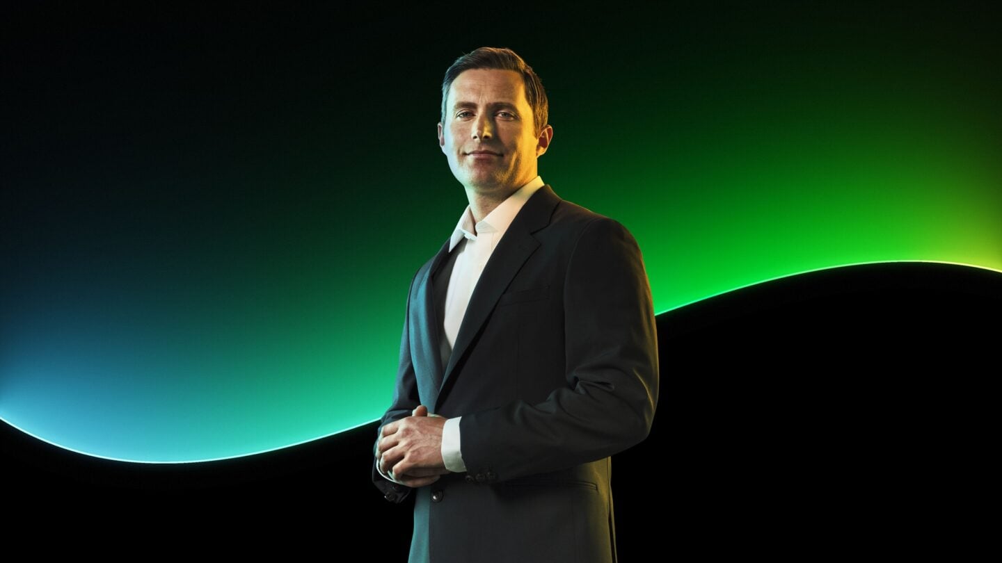 A man poses in front of the Sage glow line and a black background.