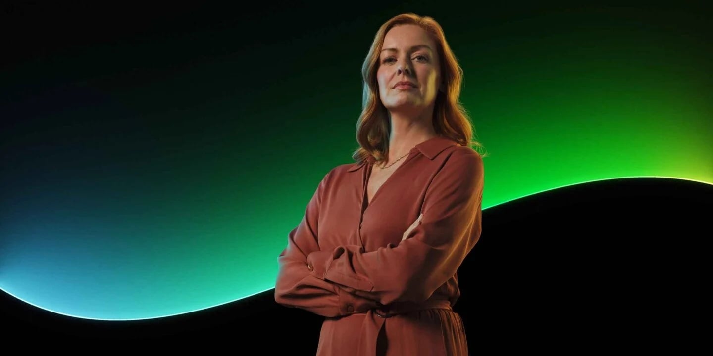 A woman stands in front of the Sage glowline in front of a black background.