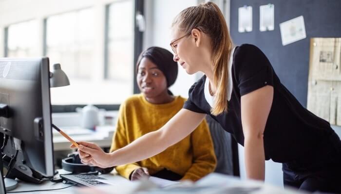 two office workers collaborating on a desktop computer