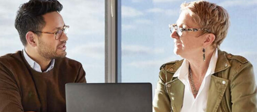 man and woman talking with a laptop between them