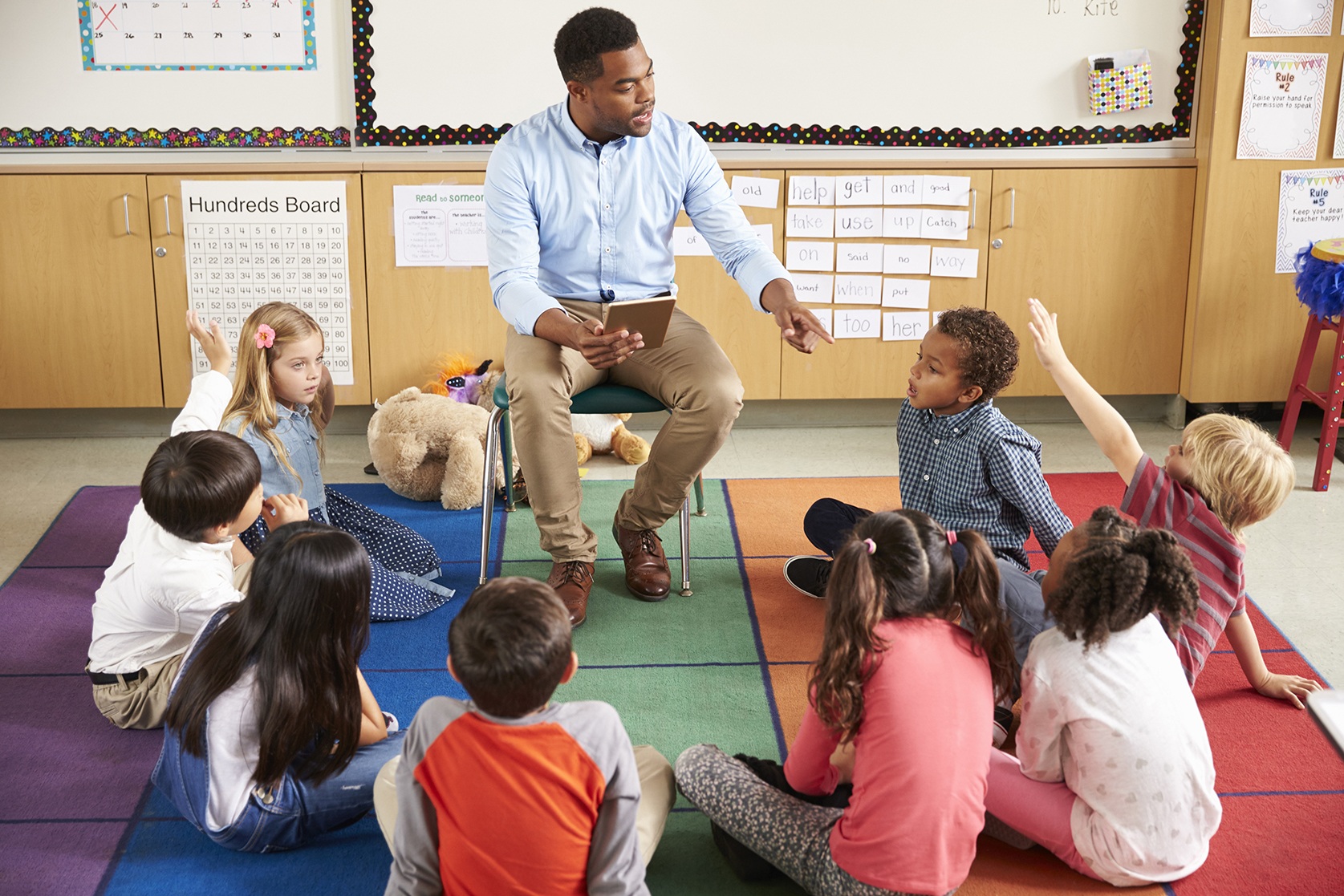 Adult black male teaching kids sitting at his feet