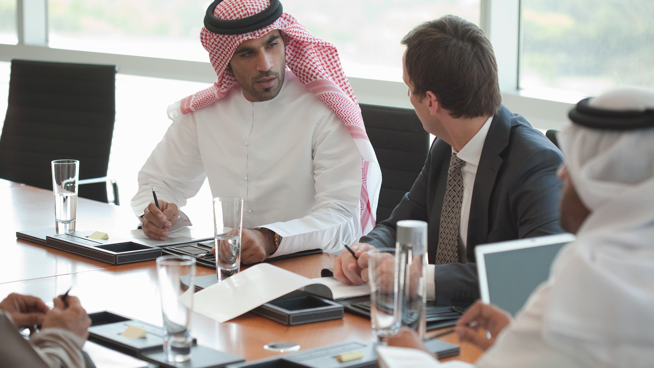 A man in suit and an Arab-dressed man having a meeting at a table