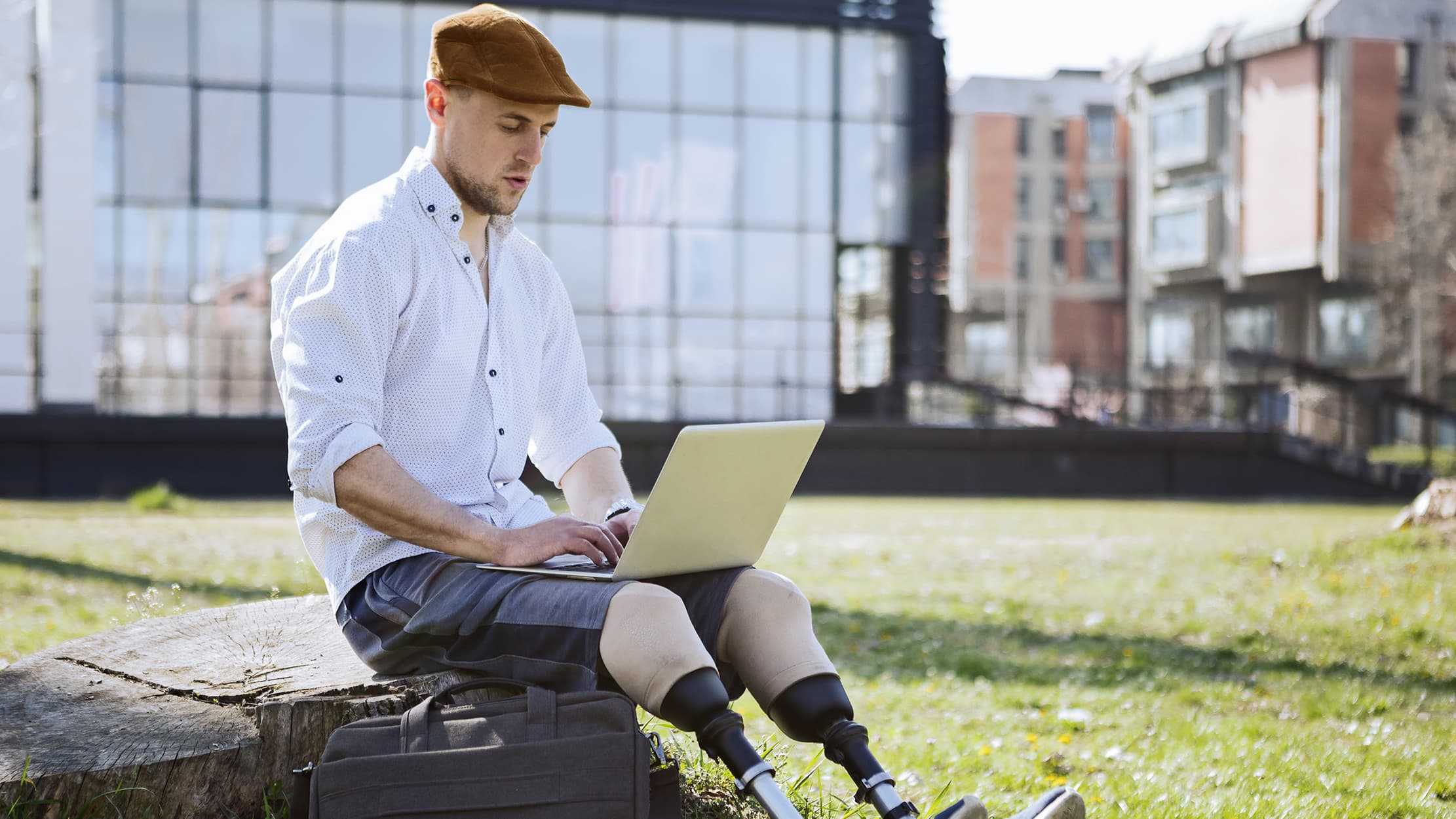 Man with artificial legs working on laptop outdoor