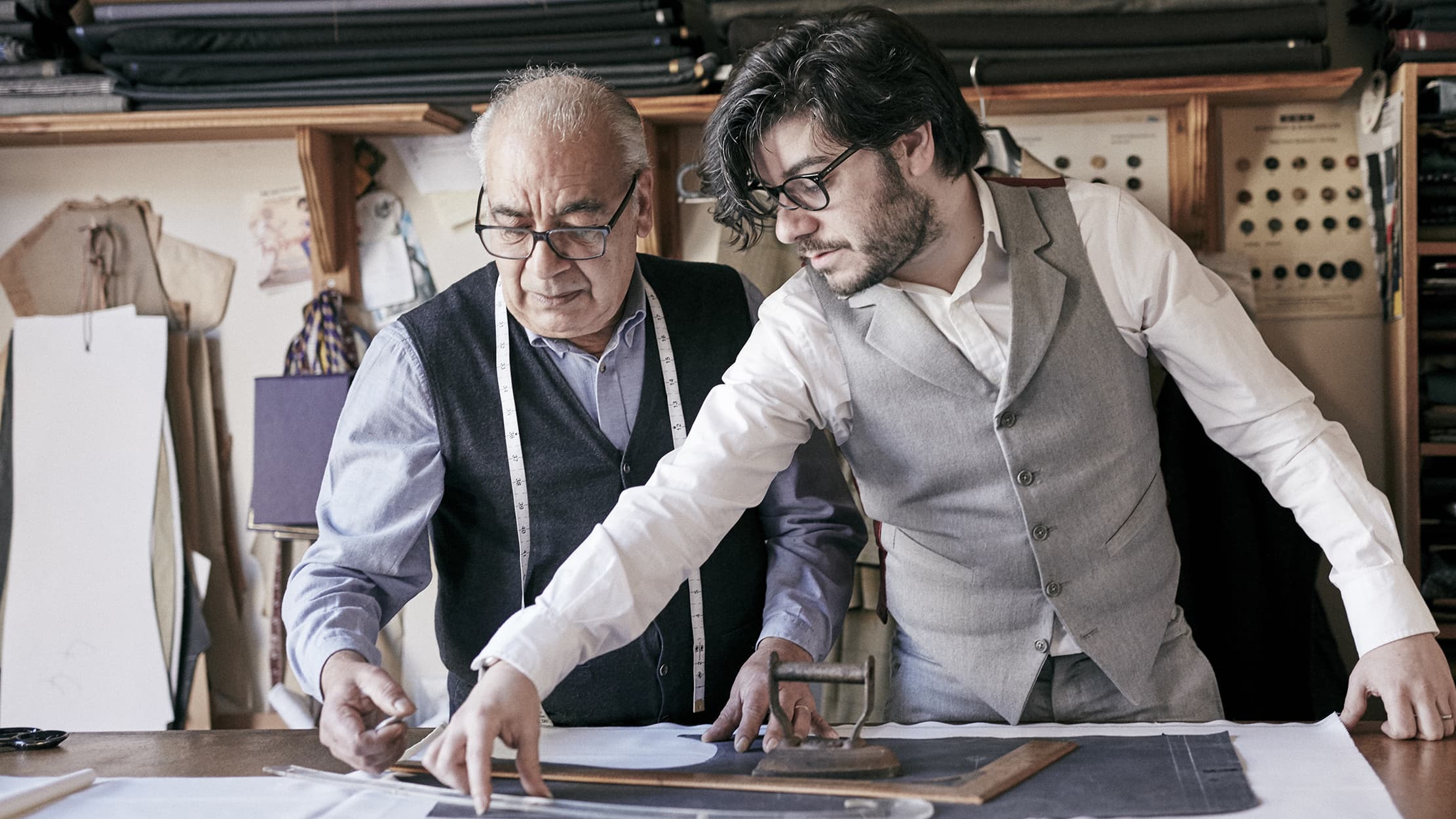 An old man and a young man drawing out plans on a table