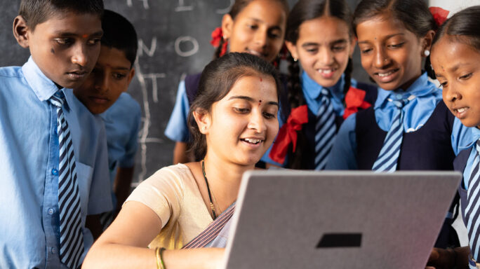 Indian teacher showing students something on computer
